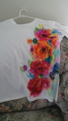 a white t - shirt with colorful flowers on it is sitting on a floral couch