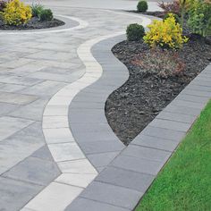 an outdoor walkway is shown in the middle of a yard with flowers and shrubs on either side