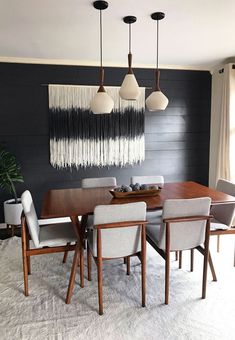 a dining room table with white chairs and black wall hangings above it, along with an area rug on the floor