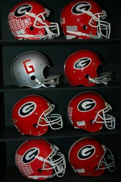 several football helmets are lined up on shelves