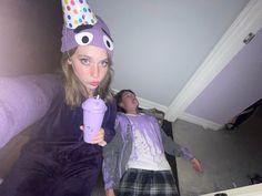 a girl in a party hat drinking from a purple cup