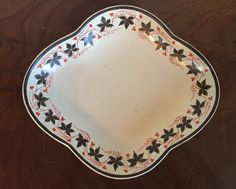 a white plate with black and red designs on the rim sitting on a wooden table