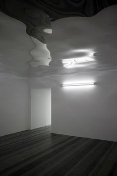 an empty room with white walls and wooden floors is lit by recessed lights in the corner