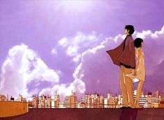 two people standing on top of a roof in front of a cityscape with clouds