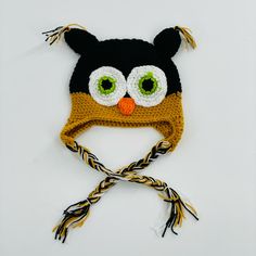 a knitted hat with an owl's face on it, tied to a string