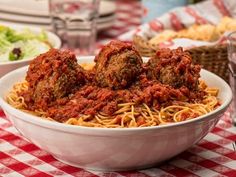 spaghetti and meatballs are served in a bowl on a red checkered tablecloth