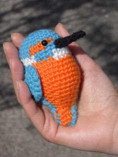 a small blue and orange bird in someones hand