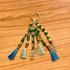 a keychain with beads and tassels hanging from it on a wooden surface