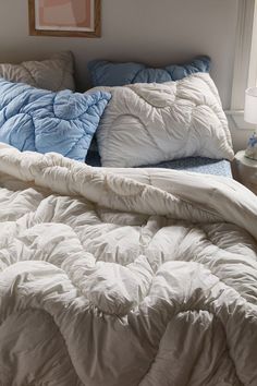 an unmade bed with blue and white pillows