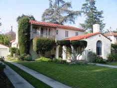 a white house with red roof and green lawn