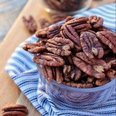 a bowl full of pecans sitting on top of a wooden table