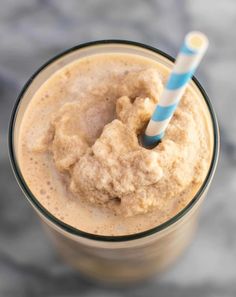 a smoothie in a glass with a blue and white striped straw sticking out of it