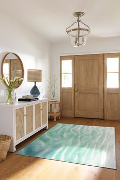 a living room with wooden doors and white rugs on the hardwood floor next to it