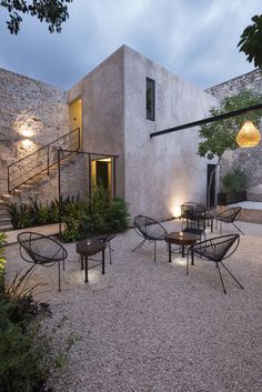 an outdoor area with chairs, tables and lights on the side of the building is lit up at night