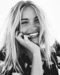 black and white photograph of smiling woman with hand on chin, looking to the side