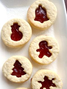 four cookies with jam in the middle on a white plate