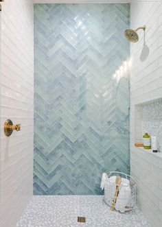 a bathroom with blue and white tiles on the walls, shower head, and shelf