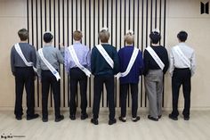 a group of people standing in front of a wall with sashes on their backs