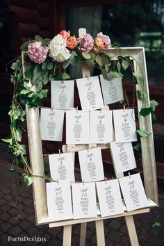 an easel with seating cards and flowers on it