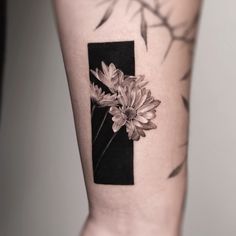 a black and white photo with flowers on the side of a woman's leg