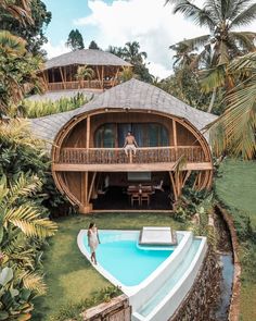 two people standing on the roof of a house next to a swimming pool with a boat in front of it