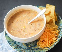 a bowl of dip with cheese and chips on the side, ready to be eaten