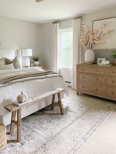 a bed room with a neatly made bed and a wooden bench in front of a window