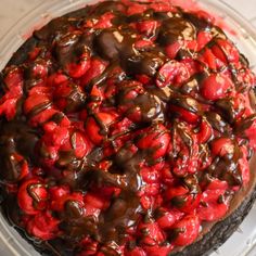 a chocolate and strawberry cheesecake on a clear platter with red strawberries in the center