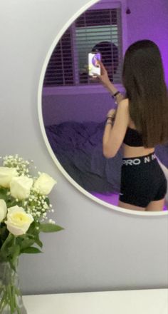 a woman taking a selfie in front of a mirror with flowers and a vase