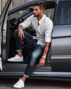 a man sitting in the back of a car with his foot on the door handle