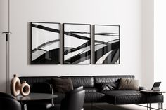 three black and white paintings hang on the wall above a leather couch in a modern living room