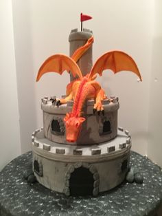 there is a cake that looks like a dragon sitting on top of a castle tower