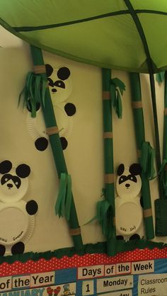 some panda bears are hanging on the wall in front of paper plates and bamboo sticks