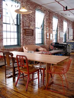 an industrial loft with exposed brick walls and wooden floors, dining table surrounded by chairs