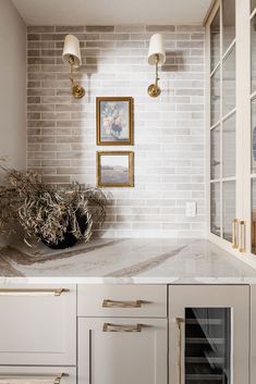 a white kitchen with marble counter tops and gold trim on the cabinets, along with a dishwasher