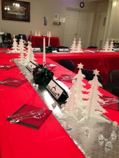 a red table topped with lots of white trees and place settings on top of it