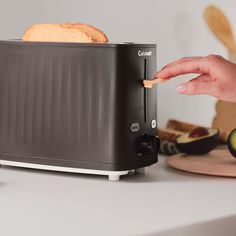 a toaster sitting on top of a counter next to sliced cucumbers and bread