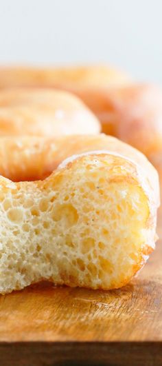 two glazed donuts sitting on top of a wooden cutting board