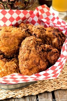 fried chicken in a basket next to a glass of beer