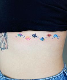 a woman's stomach with an ocean themed tattoo on the side and under her belly