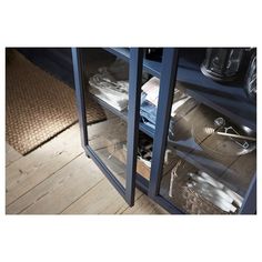 an open cabinet with dishes and utensils in it on the floor next to a rug