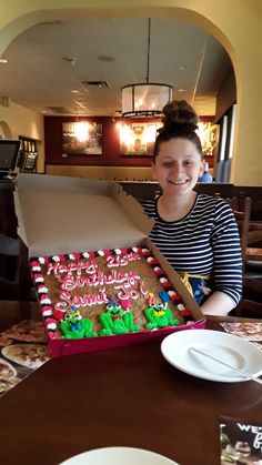 a woman sitting at a table with a large gingerbread cake in front of her