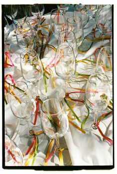 many wine glasses are lined up on a table with ribbons and streamers around them