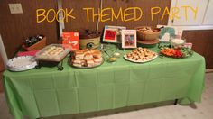 a green table topped with lots of food next to a sign that says book themed party