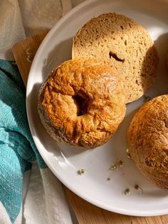 three pastries on a white plate sitting on a wooden table next to a blue towel