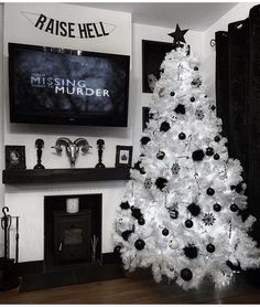 a white christmas tree with black ornaments in front of a television mounted on the wall