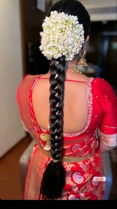 the back of a woman's head with long braids and flowers in her hair