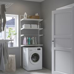 a washer sitting next to a window in a room with shelving on the wall