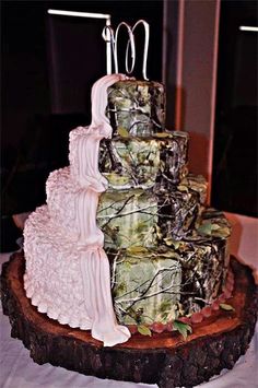 a three tiered wedding cake on top of a tree stump with mossy decorations