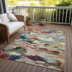 a colorful rug on a porch next to a couch and chair with potted plants